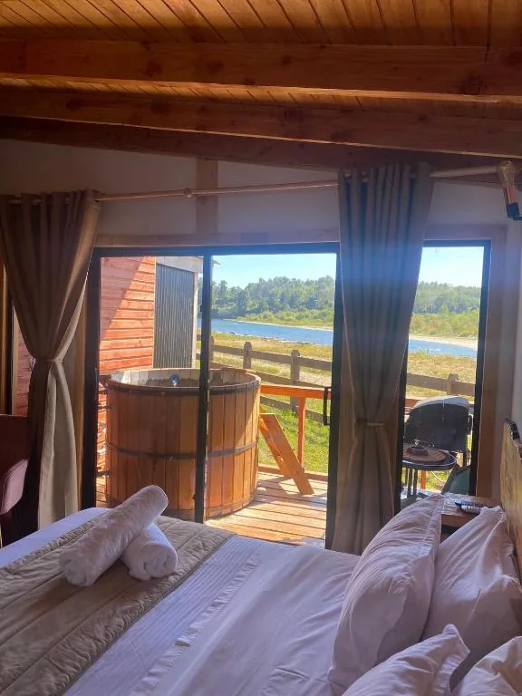 Interior de cabaña con vista al río y tinaja en Paraíso Wilkeco