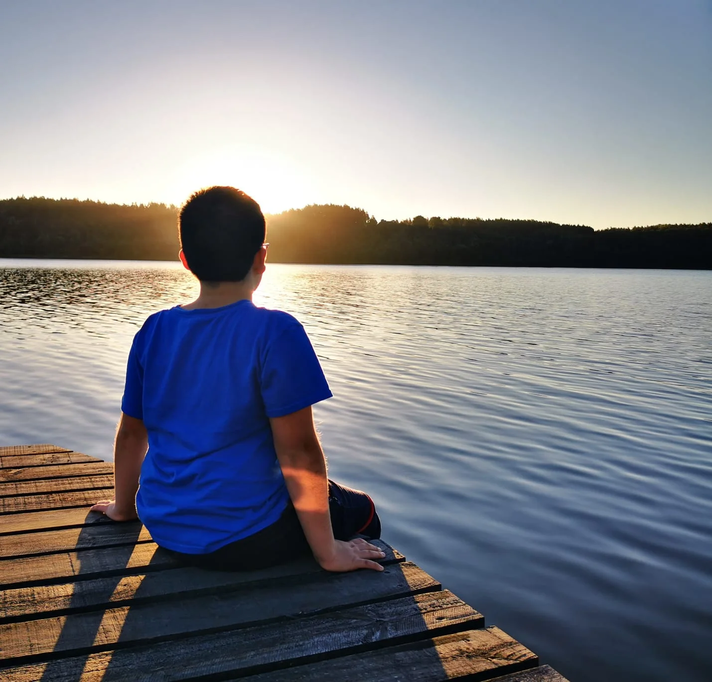 Niño contemplando el atardecer desde el muelle en Paraíso Wilkeco
